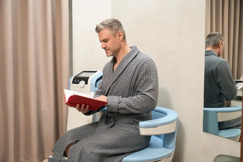 Man sitting comfortably during an Emsella pelvic floor therapy session for erectile dysfunction treatment at Ivy Collaborative Healthcare in Augusta, GA